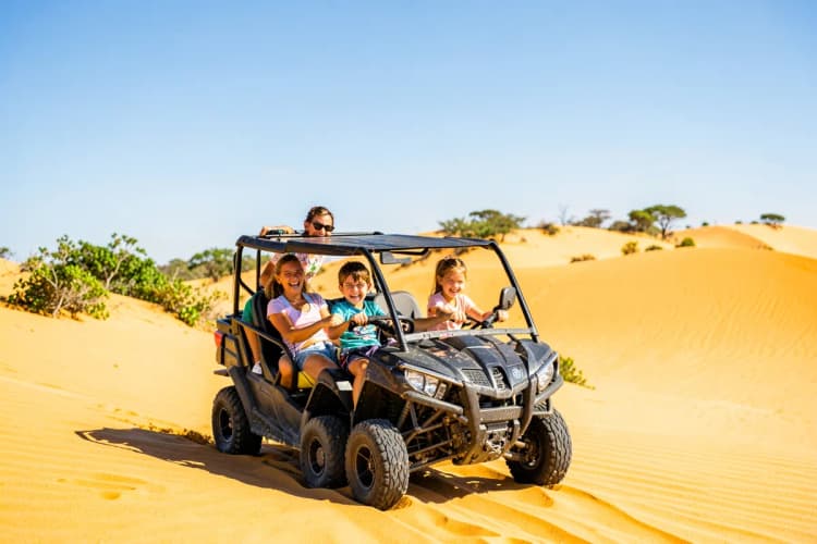 Família sorrindo em um passeio de buggy pelas dunas de Jericoacoara com céu azul