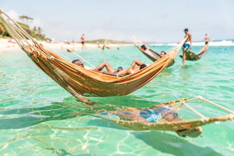 Pessoas relaxando em redes dentro da água em uma lagoa de Jericoacoara.