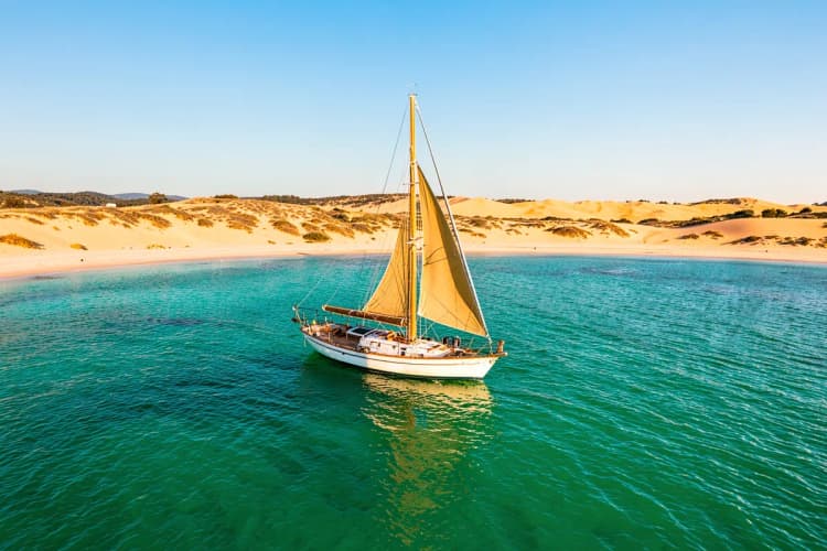 Barco a vela navegando em águas cristalinas perto da costa de Jericoacoara.