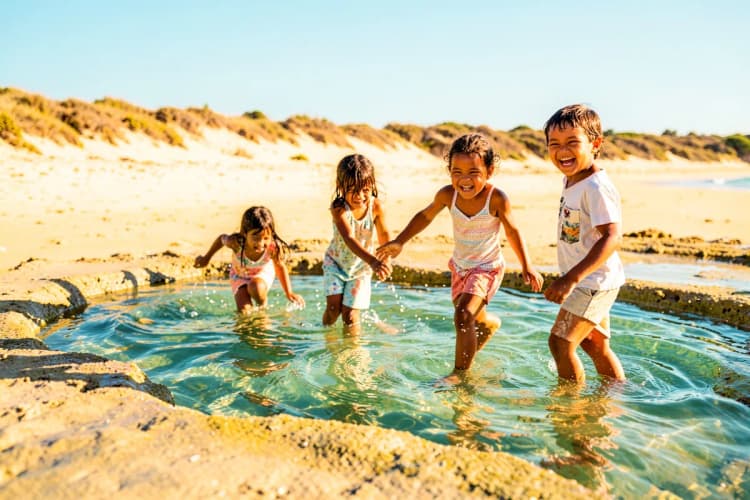 Crianças brincando em piscinas naturais formadas na maré baixa em Jericoacoara.